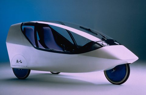 A white streamlined two-seat three-wheeler with a tinted canopy and blue wheel covers against a blue backdrop.