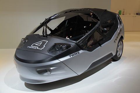 Silver and carbon-black two-seater with a large 4 on the bonnet, on a white stand. Opens a larger view
