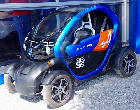 Blue and black tandem two-seater with Alpine and 36 35 lettering parked on gravel by a blue building. Opens a larger view