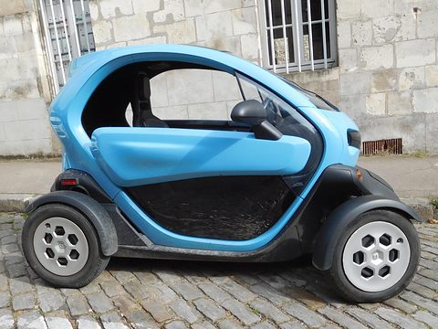 Side view of a light blue and black tandem two-seater parked on cobbles in front of a stone wall. Opens a larger view