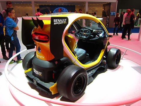 Yellow and black tandem racer with slick tyres, a rear wing and side pods, visitors around the turntable. Opens a larger view