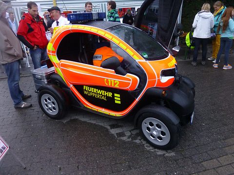 Orange and black tandem two-seater with yellow reflective stripes and Feuerwehr Wuppertal lettering, people around. Opens a larger view