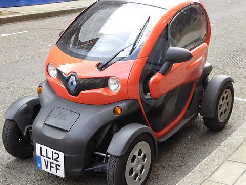 Orange and black tandem two-seater with a British plate parked at a kerb, seen from the front. Opens a larger view