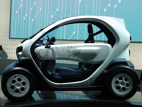 Side view of a white and grey tandem two-seater with a patterned door, on a stand with blue circuit graphics.