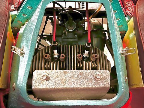 Finned twin-cylinder engine with spark-plug leads, framed by the light-blue engine cover opening.