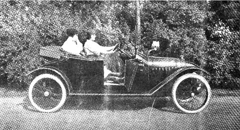 Halftone photograph of two people in a small open car with wire wheels on a path before bushes. Opens a larger view