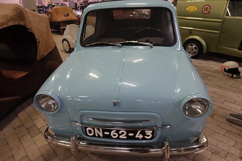 Front of a pale blue small car with a Portuguese plate, a brown tarpaulin-covered car and green van behind. Opens a larger view