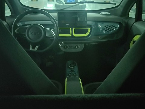 Dark dashboard with a central screen, lime-green vents and a two-spoke steering wheel between black seats. Opens a larger view