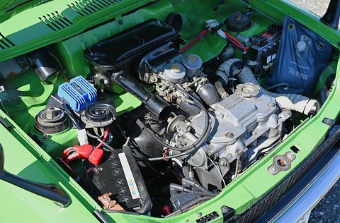 Open bonnet on a green car showing a compact engine with a blue finned cover. Opens a larger view