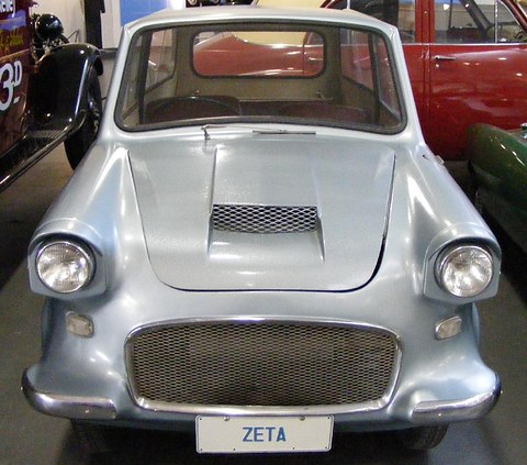 Pale blue small car seen from the front: a mesh grille, a scoop on the bonnet and a ZETA number plate. Opens a larger view